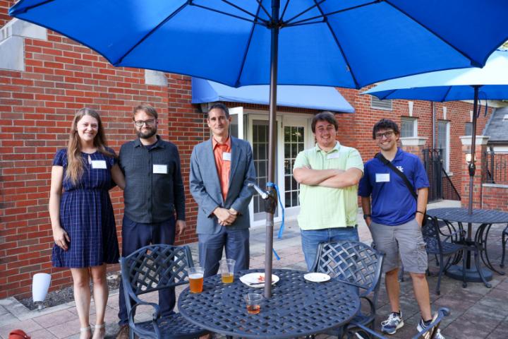 A group outside under a blue umbrella